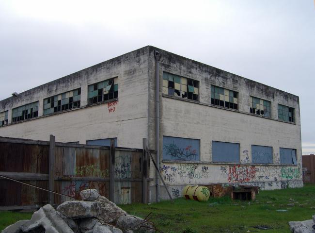 Exterior of the degraded pasta factory building before renovation at Tassafaronga Village in East Oakland, CA.