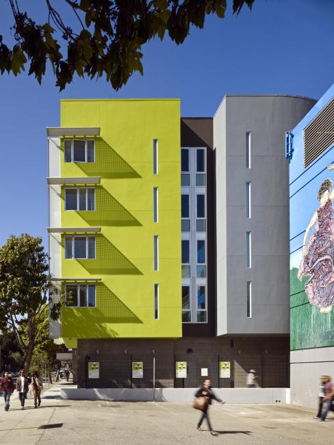 South face of the southwest corner of Richardson Apartments featuring pedestrians and bright green bay against blue sky 