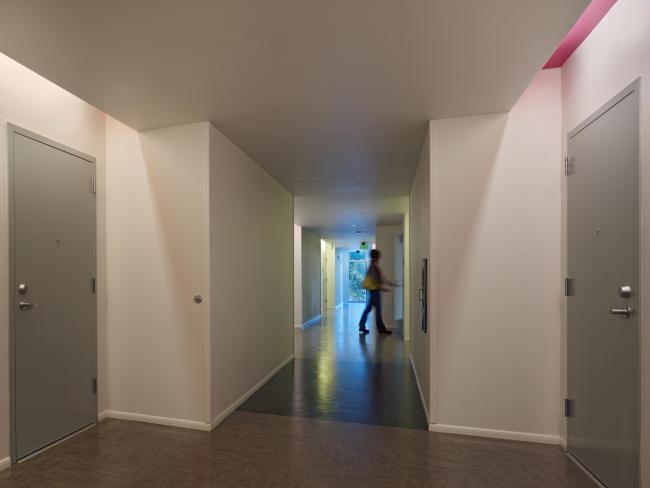 Residential corridor at Richardson Apartments, showing full-length window at hallway end and person entering apartment