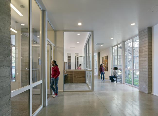 Interior hallway in ground floor of Richardson Apartments featuring transparency and daylighting, with people sitting and standing