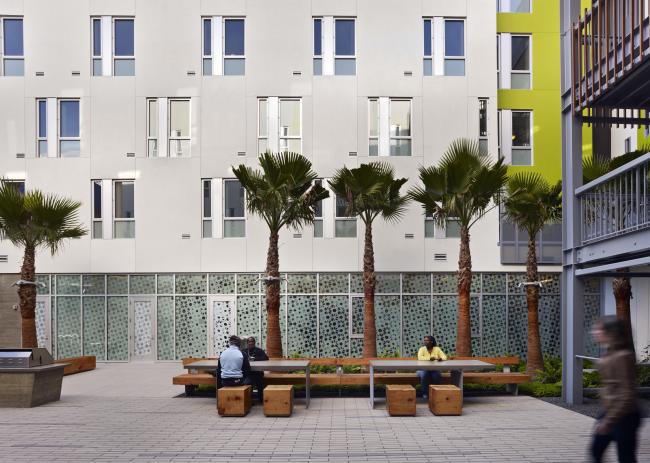 View across Richardson Apartments courtyard showing built-in furniture, palm trees, and privacy screen at on-site clinic.