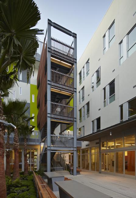 Dusk view of open-air stair in Richardson courtyard with illuminated community room at right