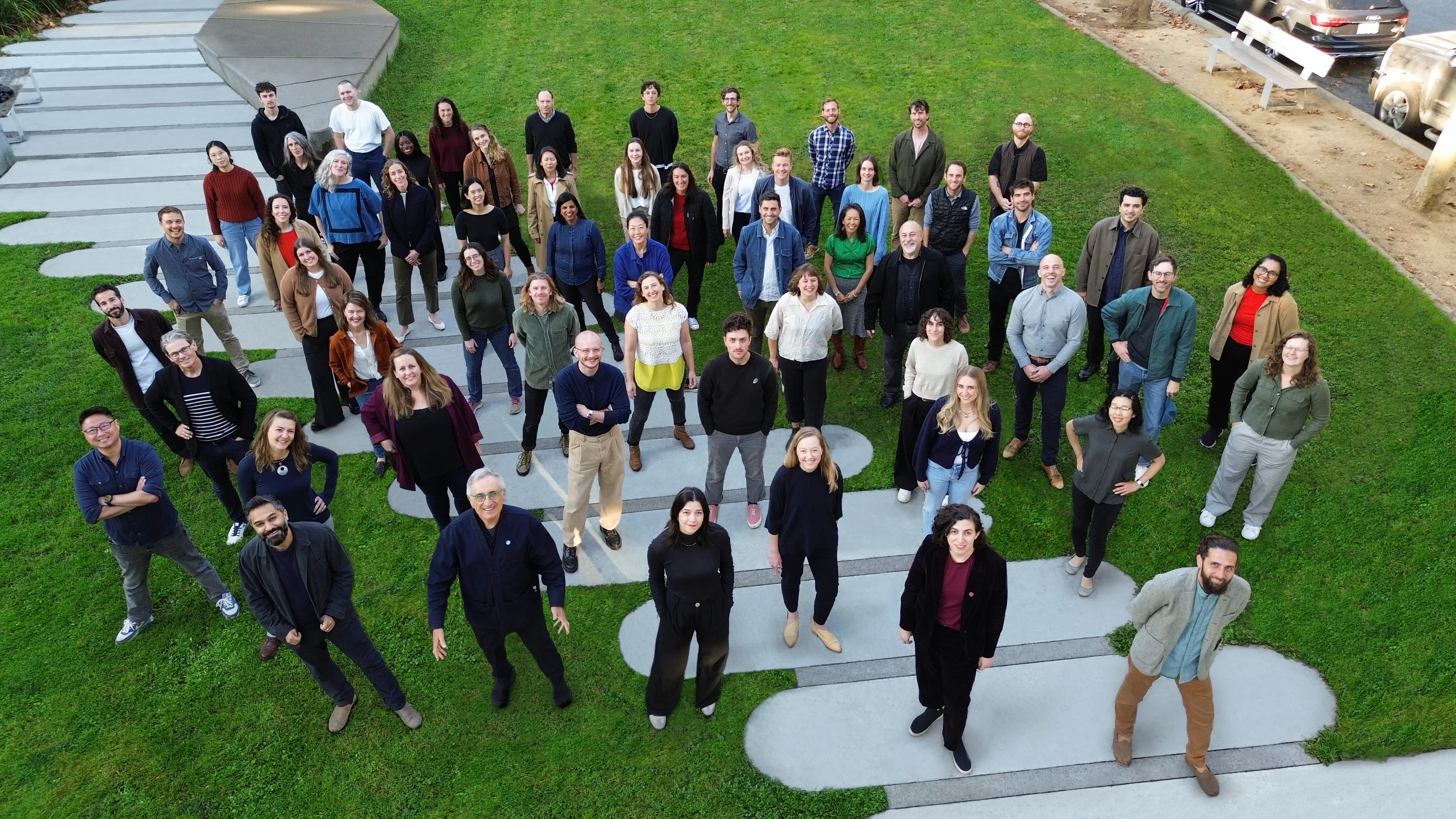 Drone photo from above of group of people standing together on grass, looking up