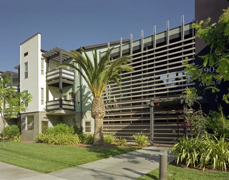 Entry surrounded by greenery and a large palm tree at Lenzen Square in San Jose, California.