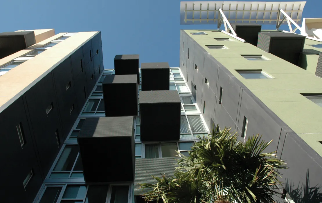 View from street looking up at underside of residential balconies and blue sky. 