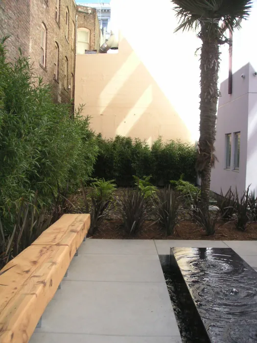 Detail showing rustic wood bench facing black, reflective meditation fountain. 