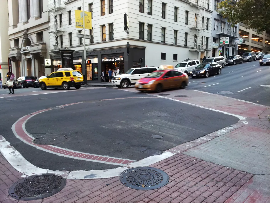 Image of an intersection that indicates a with a water cistern with a large circle brick at the intersection.