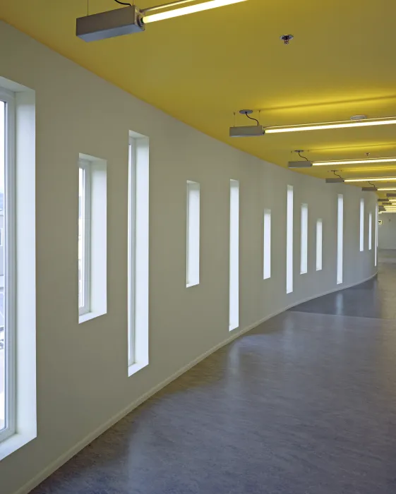 Interior corridor showing curved wall, window pattern, and yellow ceiling at Tassafaronga Village in East Oakland, CA. 