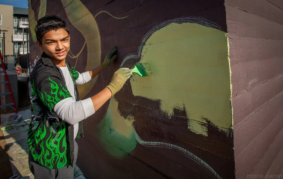 Man participating in the painting of the large sunflower mural at Station Center Family Housing in Union City, Ca.