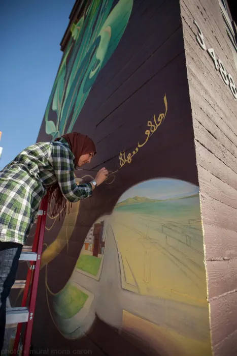 Woman participating in the painting of the large sunflower mural at Station Center Family Housing in Union City, Ca.