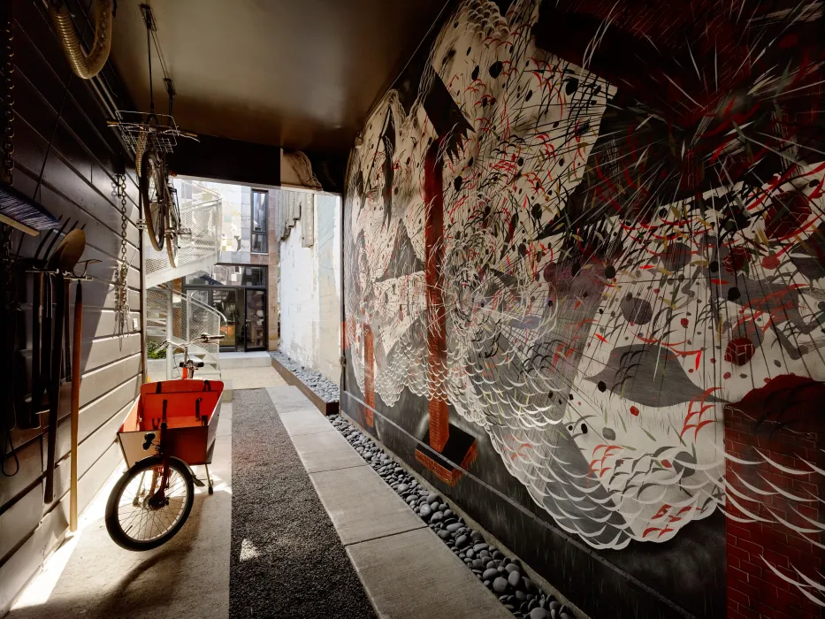 Inside passage to Zero Cottage with a red, white and black mural on the right side of the wall.