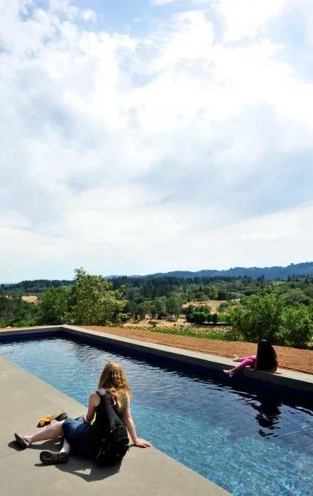 Two women sitting by the pool overlooking the hills and mountains at Healdsburg Rural House in Healdsburg, California.