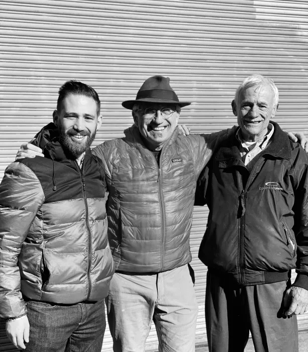 Three men standing with their arms around each other.