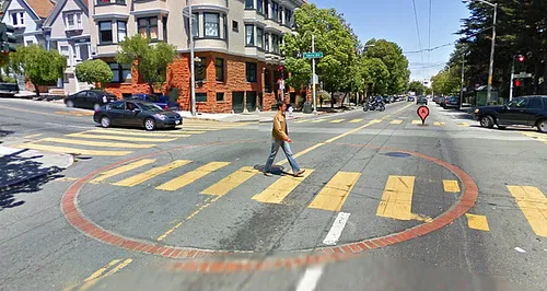 Image of an intersection that indicates a with a water cistern with a large circle brick at the intersection.