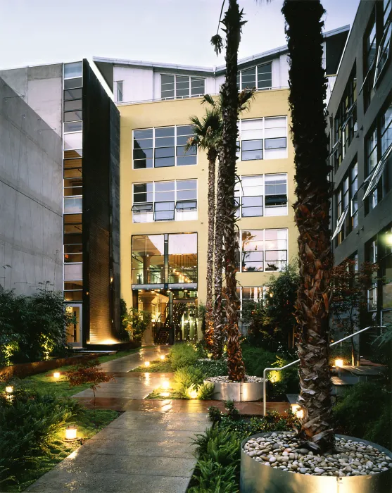 Exterior view of the entry courtyard to 1500 Park Avenue Lofts at dusk in Emeryville, California.