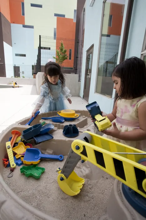 Two children playing in a sandbox at Paseo Senter in San Jose, California.