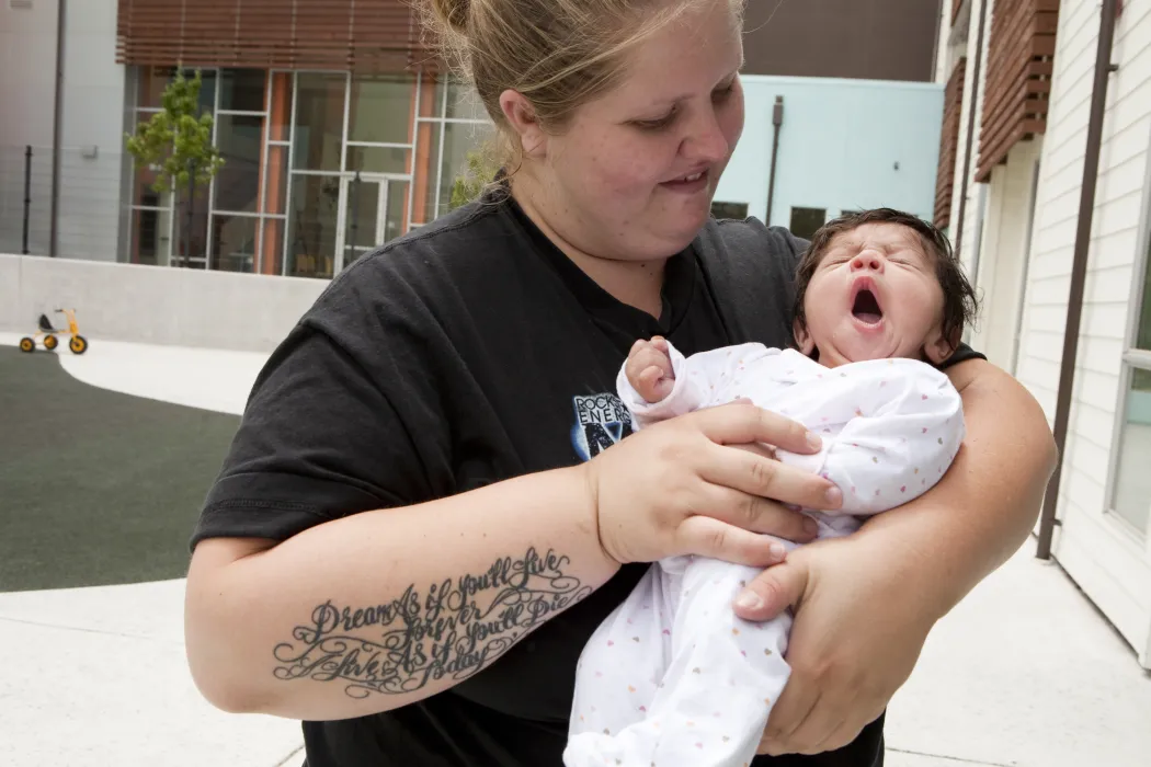 Mother holding her baby on the playground at Paseo Senter in San Jose, California.