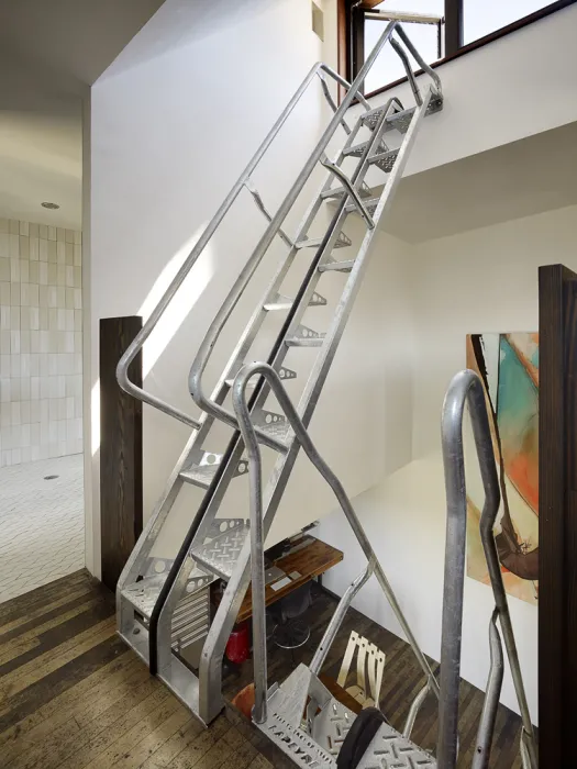 Interior view of the third level of Zero Cottage, with additional metal stairs going to the fourth level with the bathroom in the background.