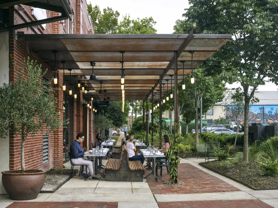 View of people sitting at tables at Bettola Patio underneath the trellis in Birmingham, Alabama.