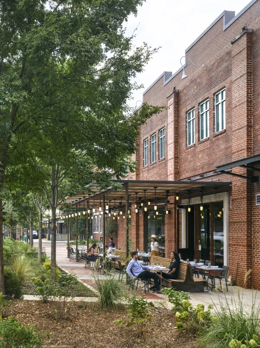 View from the southeast of people sitting at tables at Bettola Patio underneath the trellis in Birmingham, Alabama.