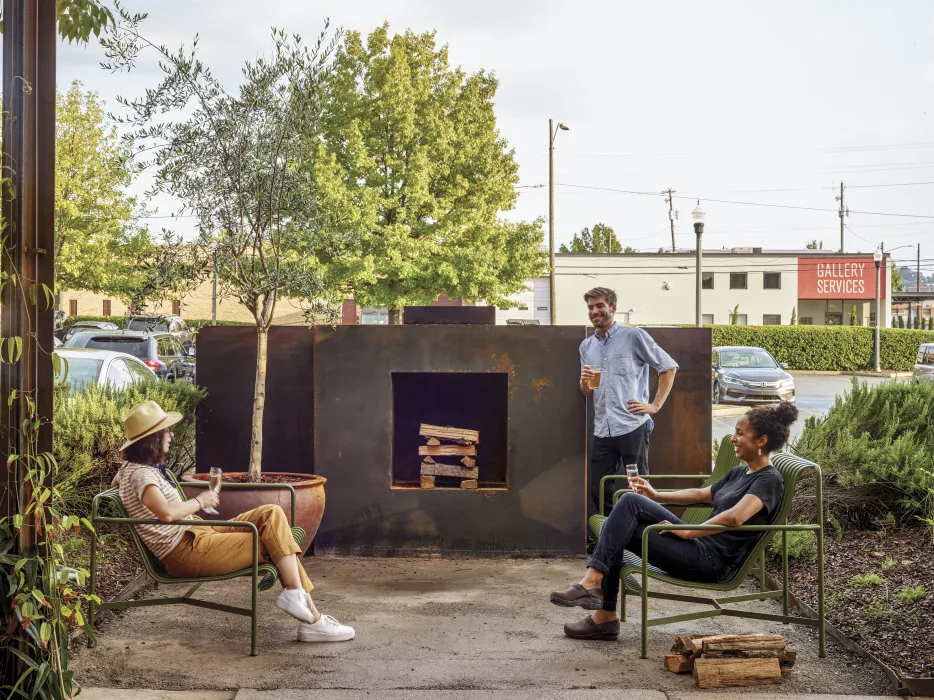 People hanging out at the outdoor steel fireplace at Bettola Restaurant in Birmingham, Alabama.