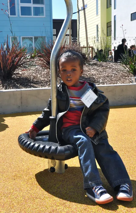 Young boy sitting down in the play area at the grand opening of Ironhorse at Central Station in Oakland, California.