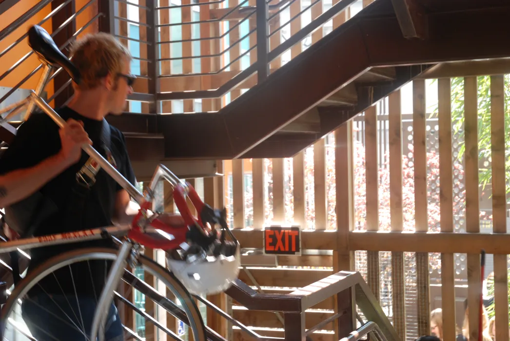 Man carrying his bike down the stairs at Folsom-Dore Supportive Apartments in San Francisco, California.