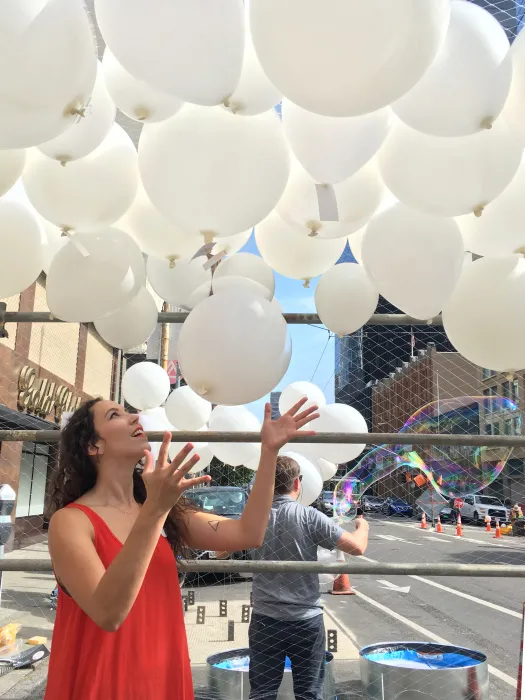 Woman holding her hands up to touch the balloons for Wishing Cloud.