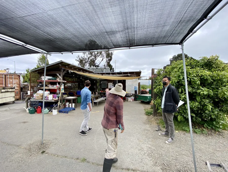 Three people standing visiting the site of the Farm2Market Shade Trellis in Alameda, California.