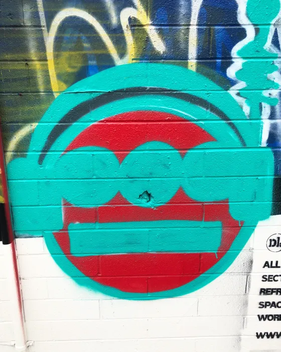 Detail of street art of a red circle with teal design over it.