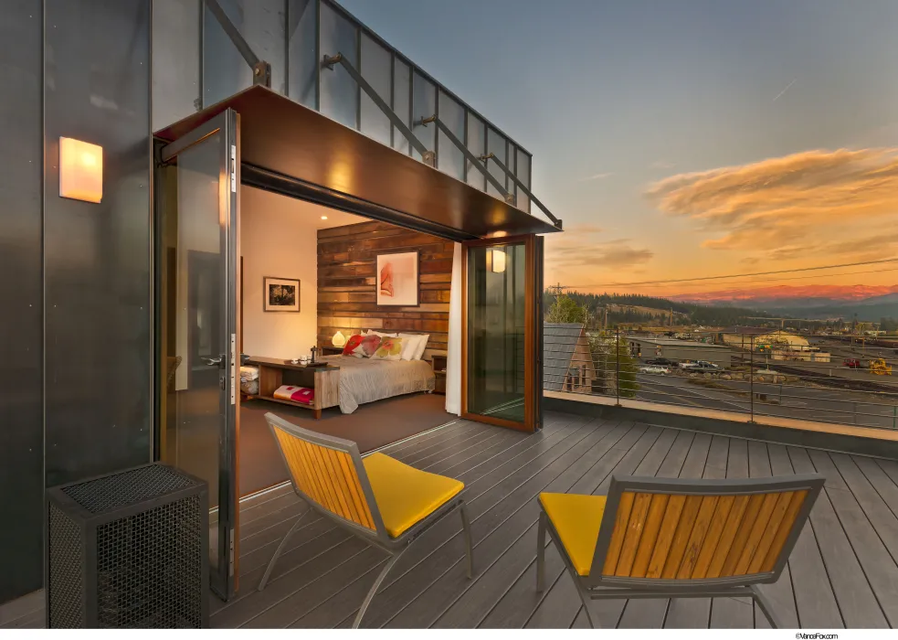Looking into the bedroom from the balcony of Truckee Prototype Mixed-Use Townhouse in Truckee, California at dusk..