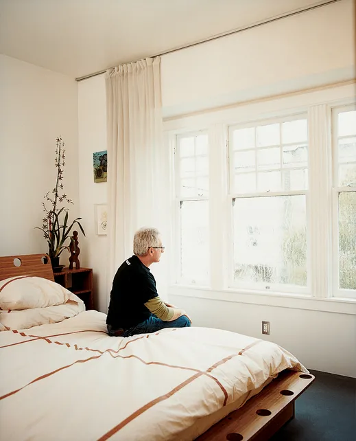 Man sitting on the bed in the master bedroom at Shotwell Design Lab in San Francisco.