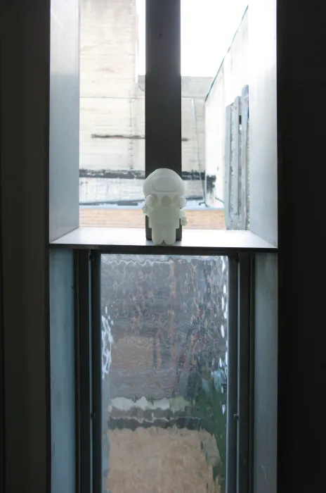 A pivot window in open position with a small astronaut figurine on it at Shotwell Design Lab in San Francisco. 