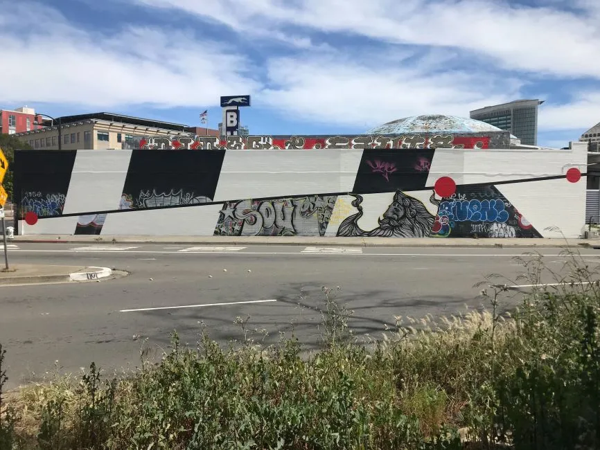 Exterior street view of the side of David Baker Architects Office covered in street art in Oakland, California.