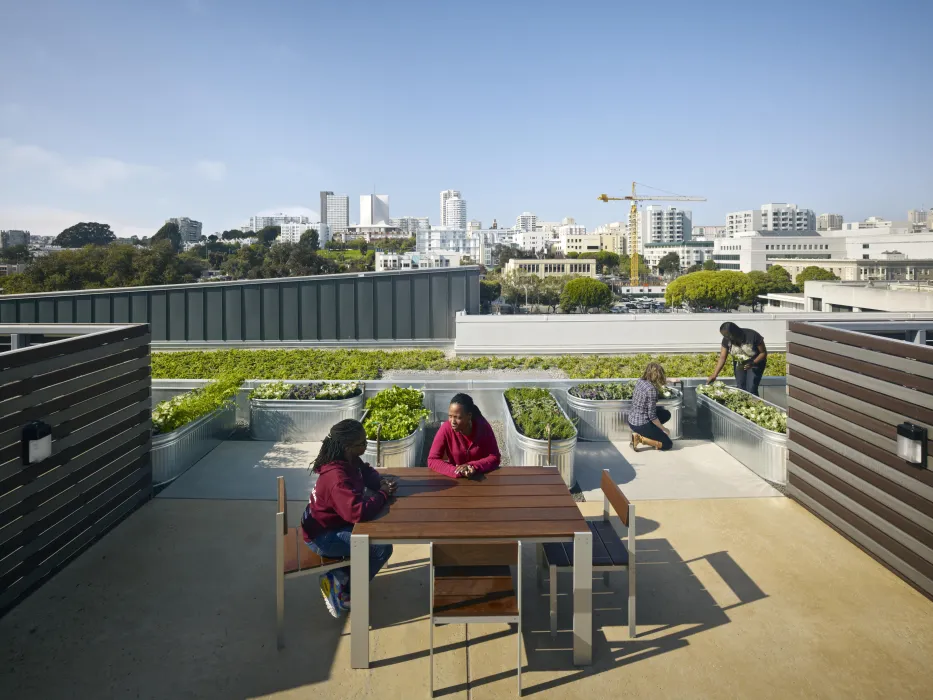 Rooftop garden beds with people sitting at table and gardening at Richardson Apartments in San Francisco.