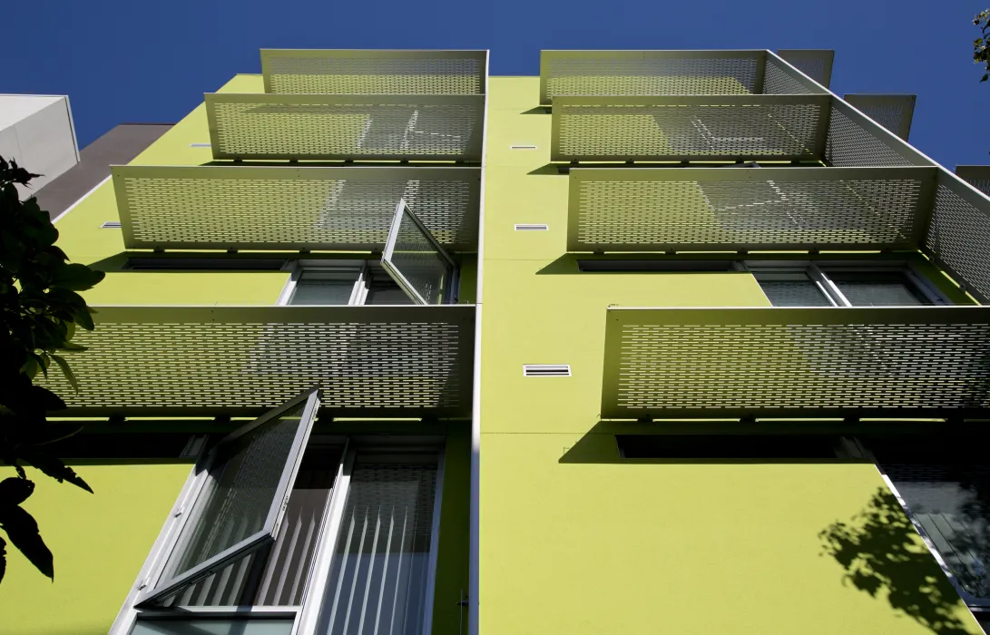 Detail of aluminum sunshades on a white and green wall at Richardson Apartments