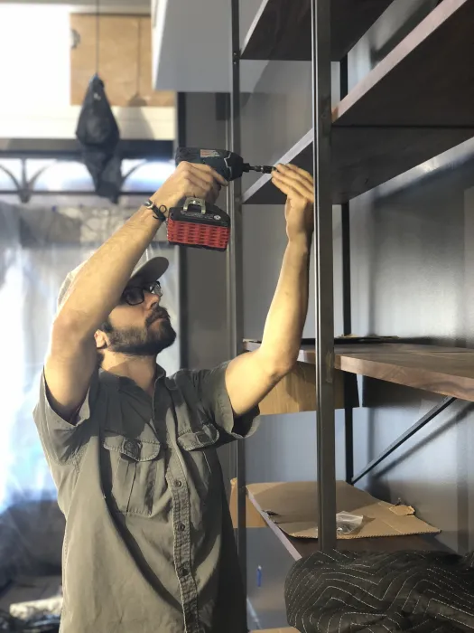 Man with a screwdriver, building a bookshelf at Civic Kitchen in San Francsico.