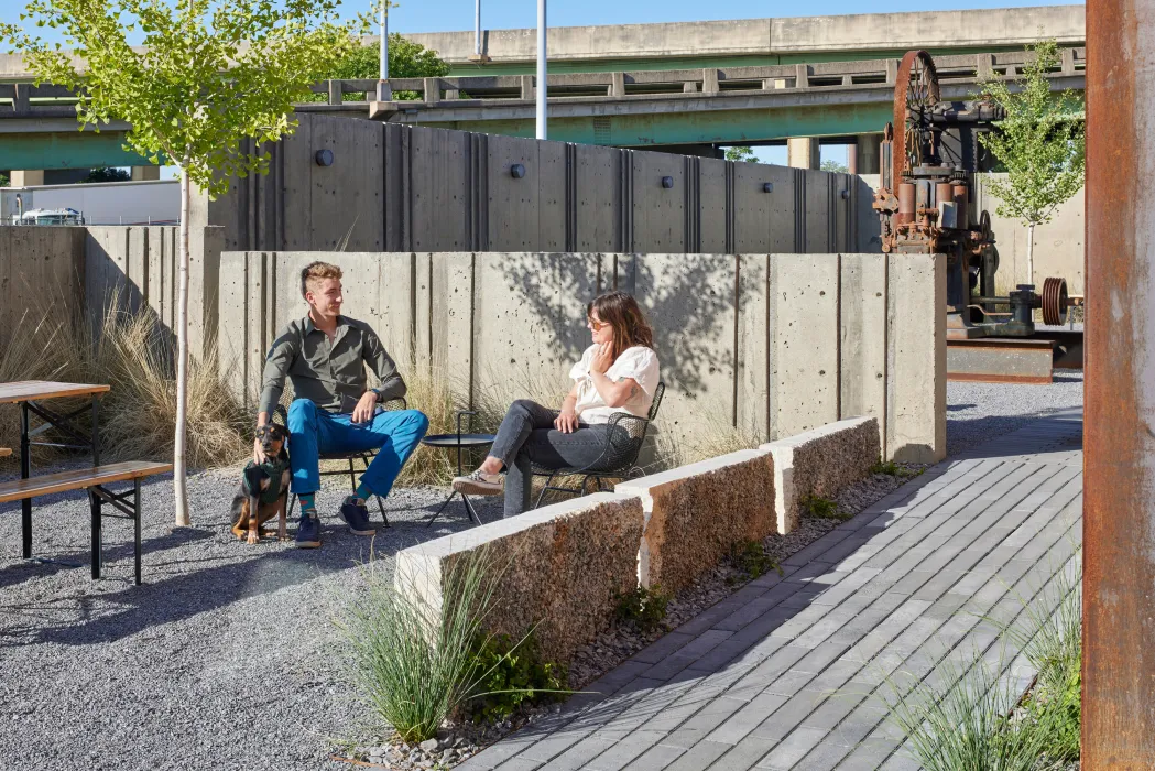 Two people and a dog sitting in the open courtyard at the Bandsaw Building in Birmingham, Alabama.