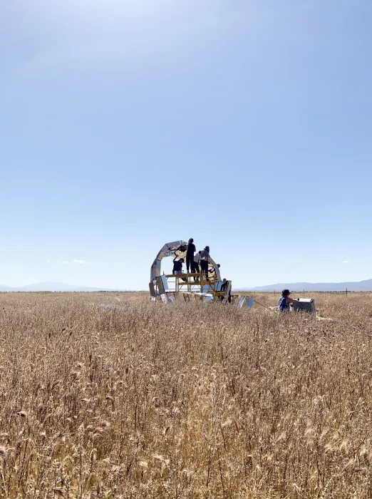 A group of people in the foreground building peepSHOW with blue skies in the desert in New Cuyama, California.