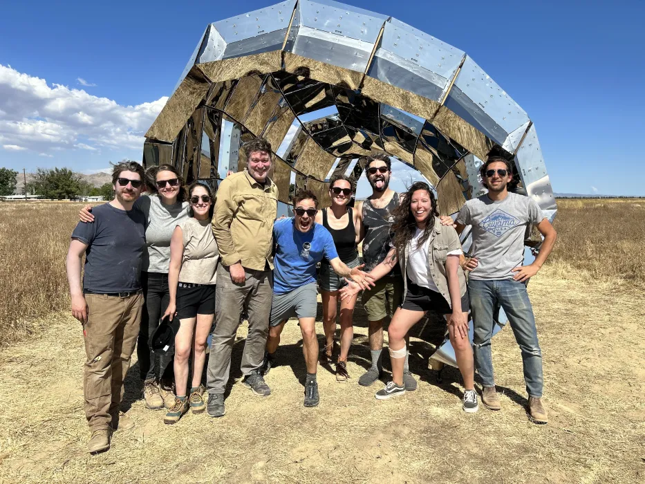 A group of people standing in front of peepSHOW in the desert in New Cuyama, California.