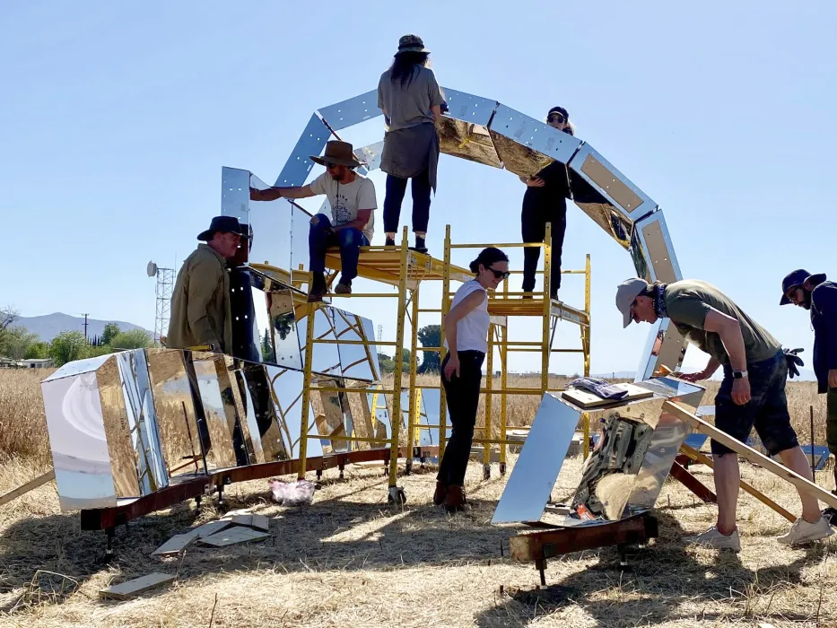 A group of people in building peepSHOW with blue skies in the desert in New Cuyama, California.