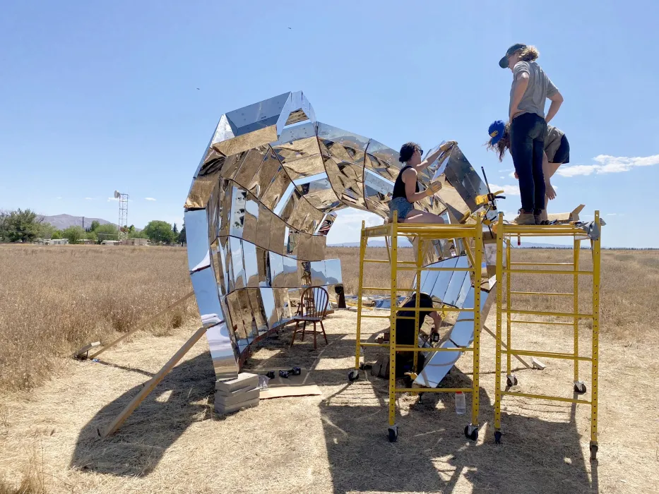 A group of people in building peepSHOW with blue skies in the desert in New Cuyama, California.