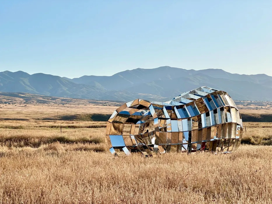 Someone walking through peepSHOW in the desert with mountains behind it in New Cuyama, California.