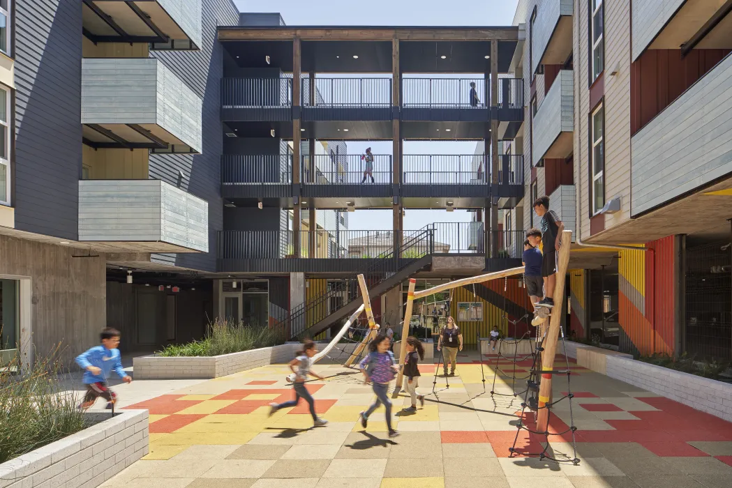 Children playing on a play structure in the courtyard of Edwina Benner Plaza in Sunnyvale, California.