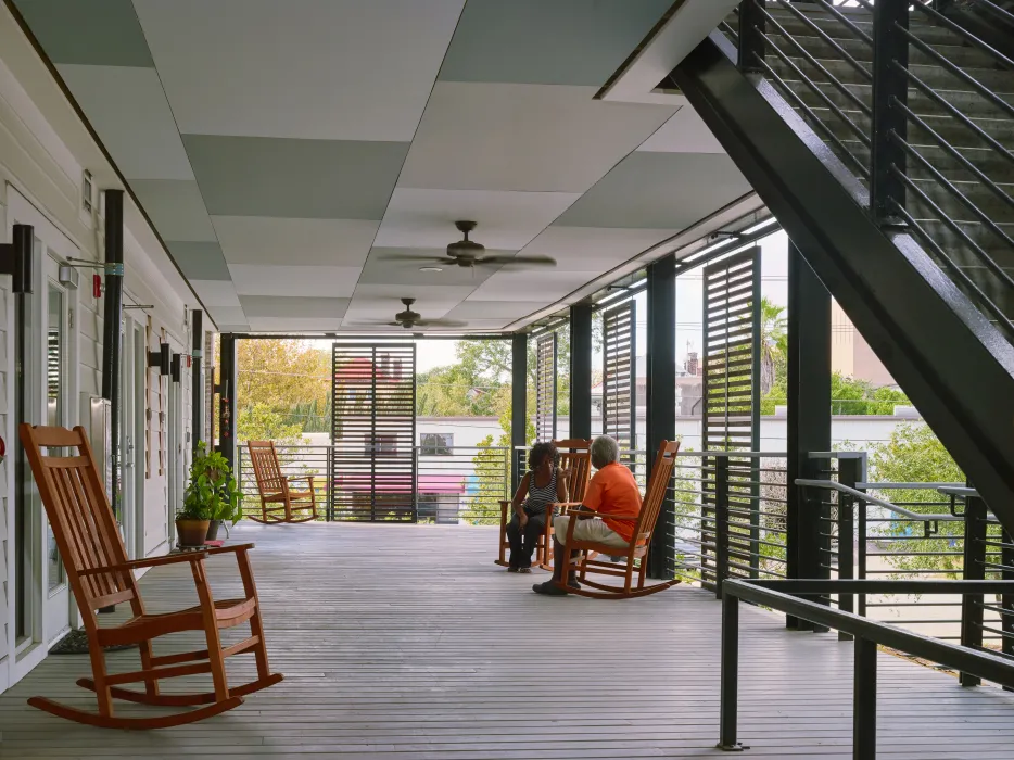 Open-air porch with two people sitting in a rocking chair at Williams Terrace in Charleston, South Carolina