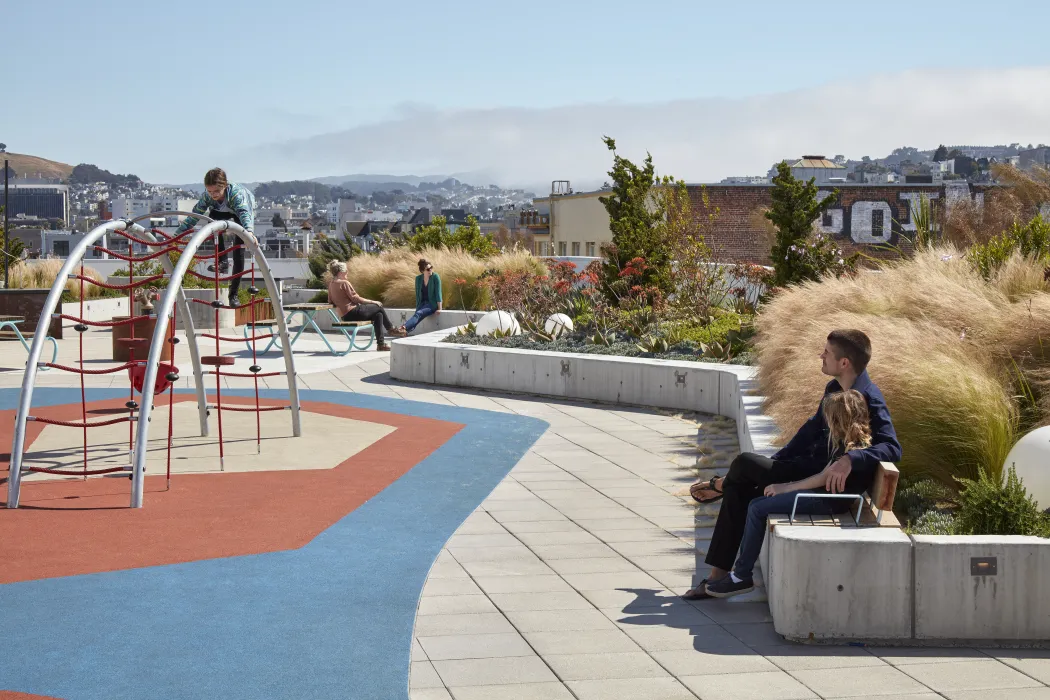 People sitting and children playing on a playground on the roof of La Fenix in San Francisco.