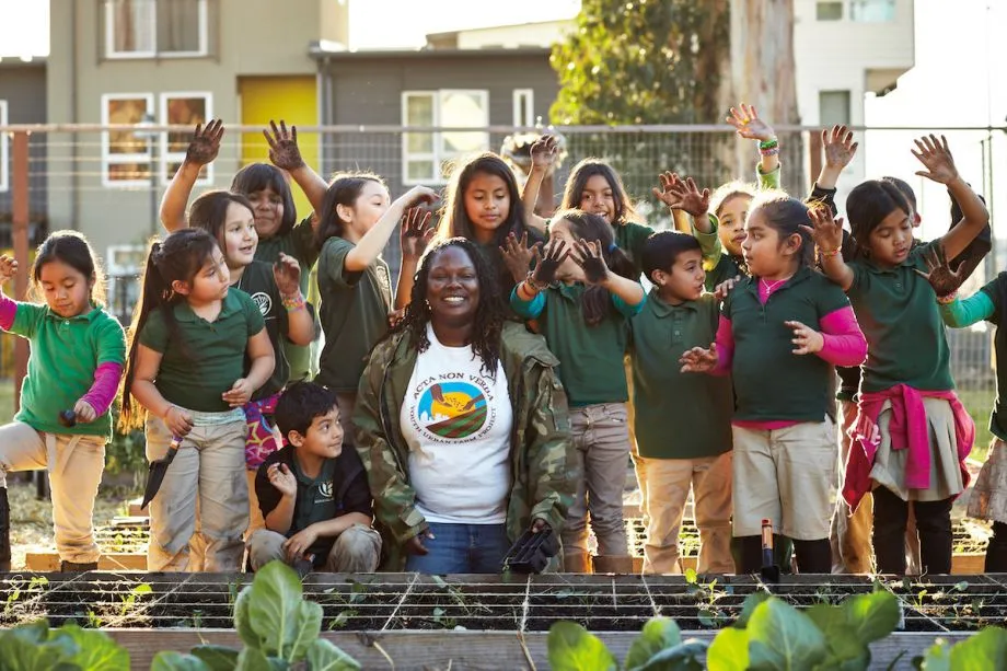 Women standing with a group of children at the Vegetation at the Acta Non Verba Farm in Oakland, California.
