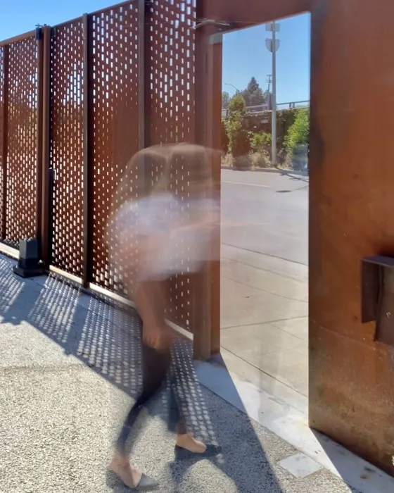 Blurred person walking through the cor-ten gate of David Baker Architects Office in Oakland, California.