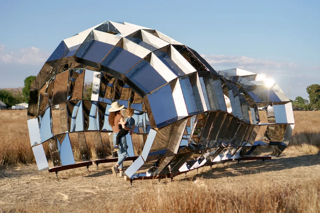 Someone walking through peepSHOW in the desert with mountains behind it in New Cuyama, California.