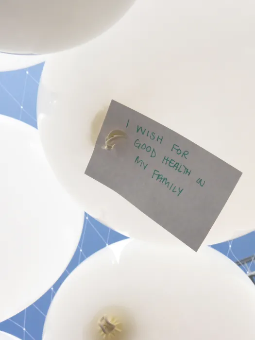 Detail of one of the Wishing Cloud balloons with the a note attached wishing for good health for their family.